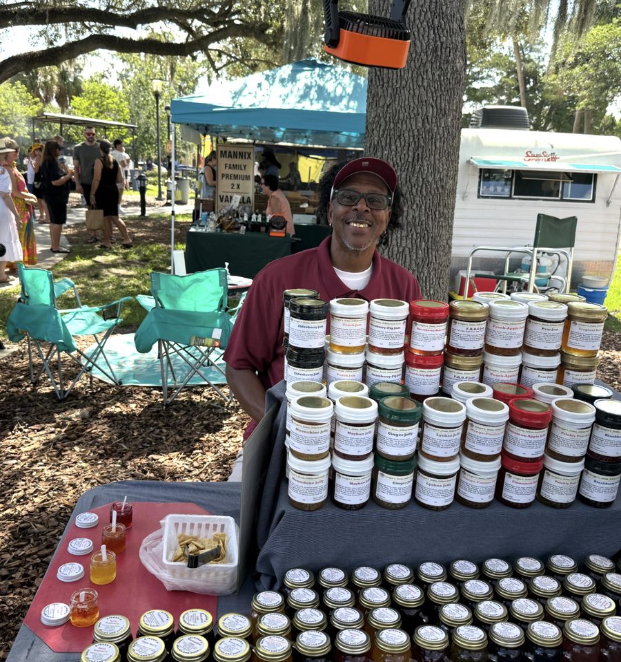 A maker behind a market table of jams and jellies